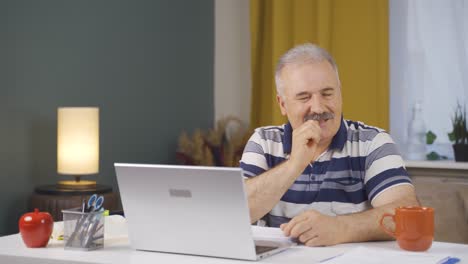 Home-office-worker-old-man-biting-his-nails-looking-at-camera.